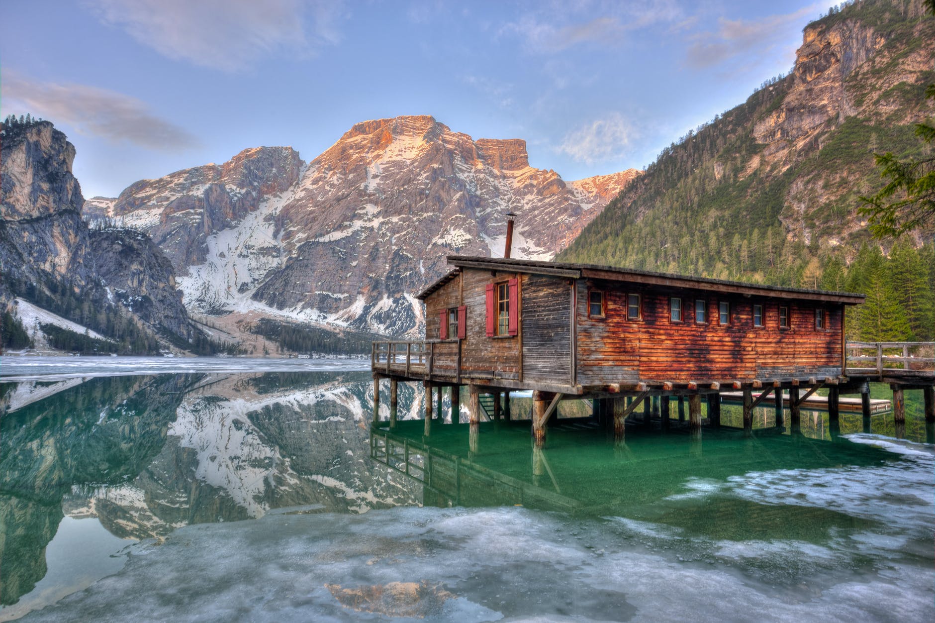 shack on body of water surrounded by mountains
